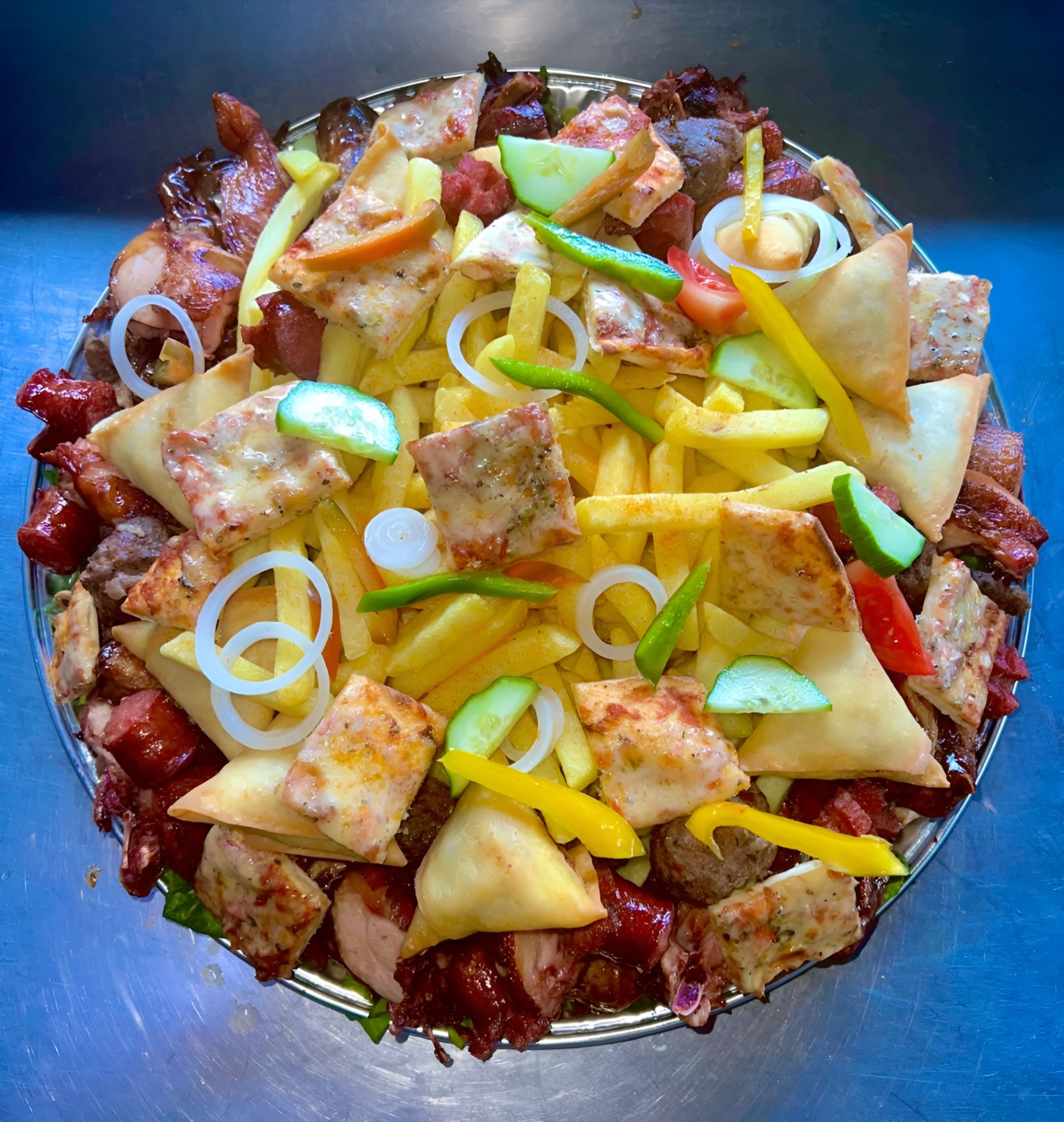 Loaded sharing platter with grilled meats, samoosas, chips and salad