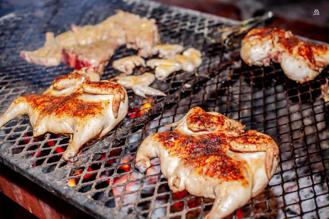 Whole chickens flame-grilling over glowing coals at The Hut Kitwe