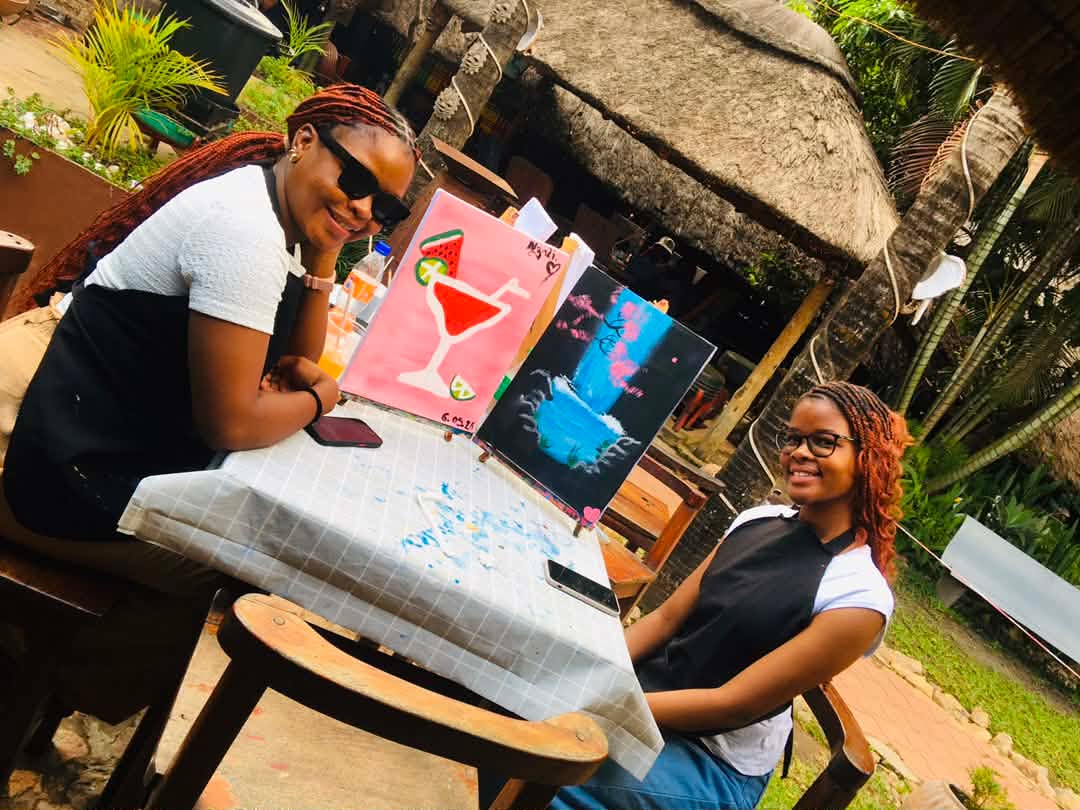 Two guests smiling with their finished paintings