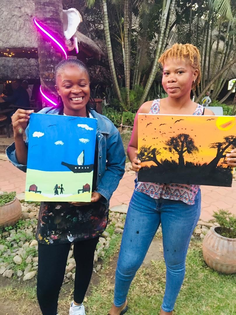 Two guests holding their finished paintings