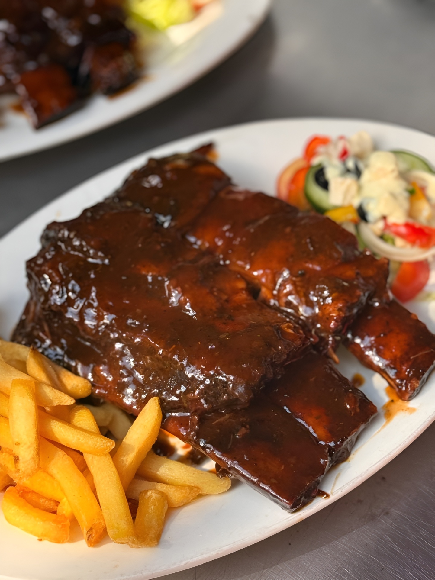 Char-grilled BBQ ribs glazed in sauce, served with chips and Greek salad