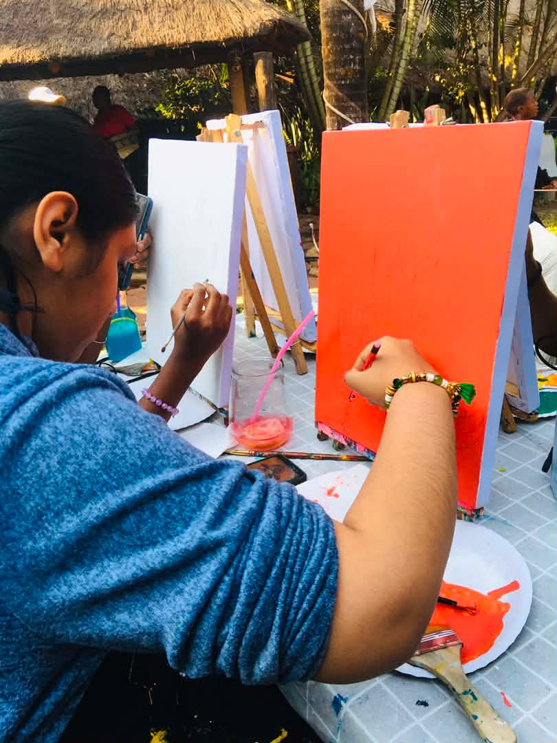 A guest painting a bright orange canvas outdoors