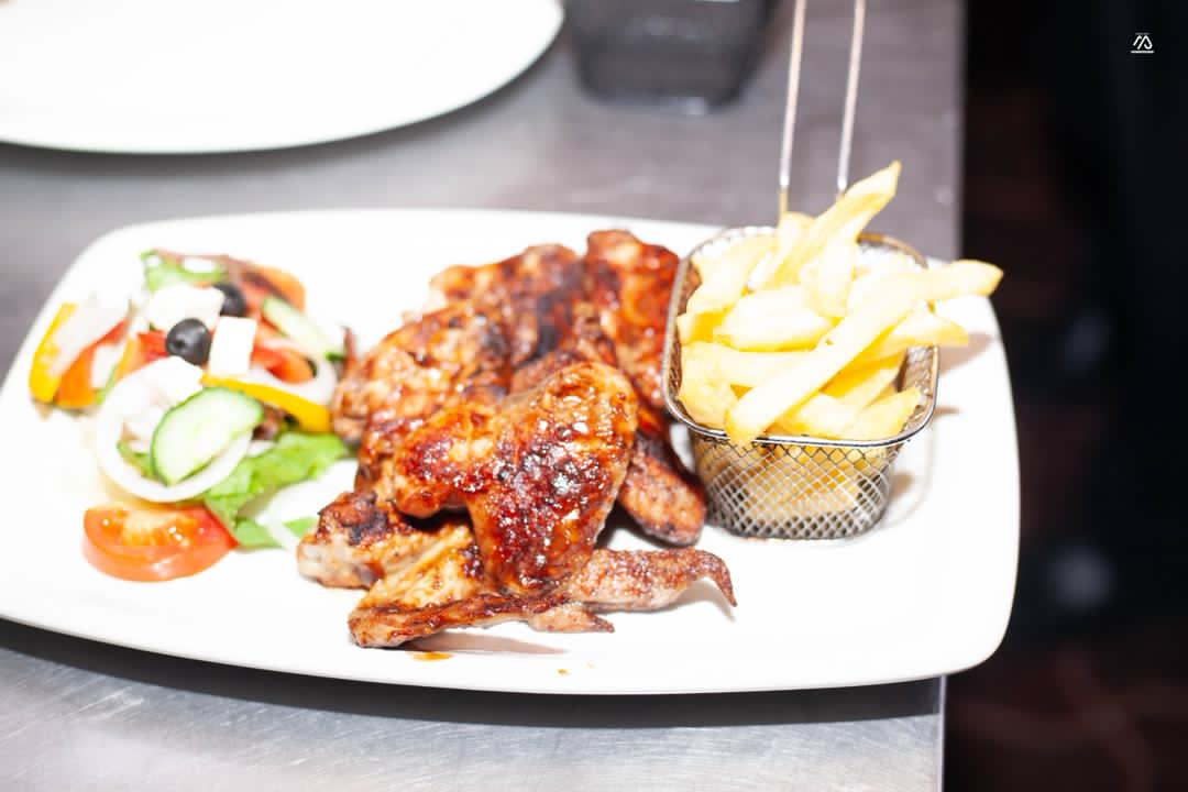 Flame-grilled chicken wings served with chips and a Greek salad